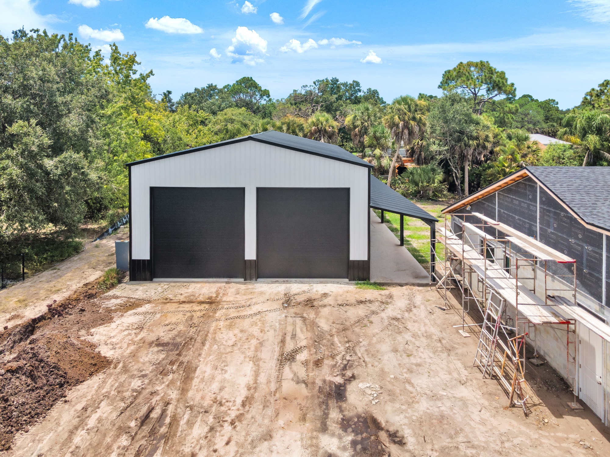 Drone progress photo of a new metal building under construction beside a structure under renovation